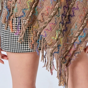 Détail du poncho en tricot marron avec motifs à vagues colorées et ourlet à franges