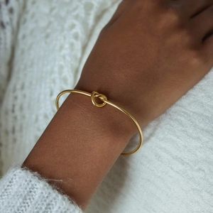 Bracciale rigido a nodo in acciaio inossidabile placcato oro 18K indossato su maglia bianca