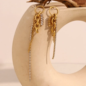 Vue détaillée des boucles d'oreilles pompons asymétriques plaquées or 18K avec strass