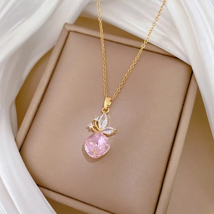 Macro detail of a golden butterfly necklace featuring pink crystal and white zircon stones