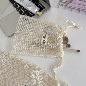 Detailed mesh lace drawstring bag featuring white daisy embroidery and branded tag