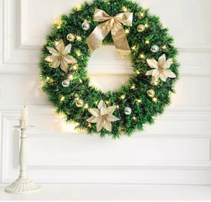 Detail of 45cm Christmas wreath with LED lights, gold bow, and white flowers on a wall