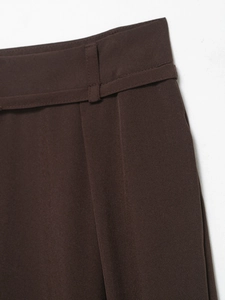 Dettaglio di pantaloni marroni a gamba larga con cintura in tessuto coordinata e trama