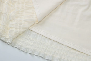 Vue macro du tissu en mousseline ivoire froncée avec doublure et couture d'ourlet fine
