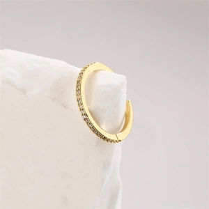 Close-up of small gold hoop earrings with sparkling cubic zirconia on a white stone