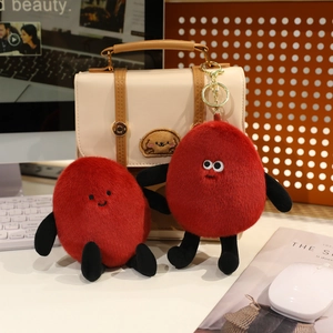Detail of red plush peanut keychains with cute quirky faces on an office desk