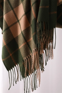 Detail shot of green and brown plaid scarf featuring soft cashmere-like texture and tassels