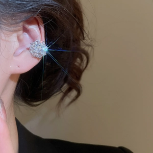 Close-up of sparkling flower zircon ear cuff with silver base on model ear