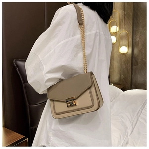 Woman wearing stylish color-block crossbody bag with gold chain strap in a cozy interior