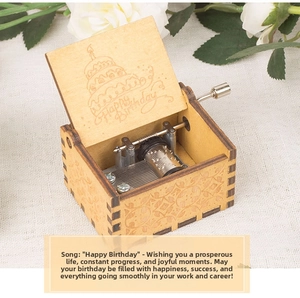 Detail of hand-cranked wooden music box with laser-engraved Happy Birthday cake design