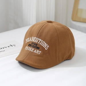 Detail of caramel canvas beret featuring white and black embroidered YUANSUTIONS text