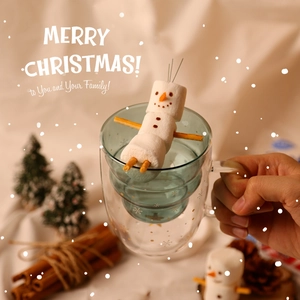 Double-walled glass Christmas mug with stars and snowman marshmallows in a festive setting