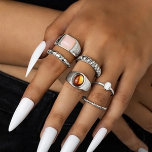 Close-up of 6-piece silver ring set with pink stones on a model with white nails