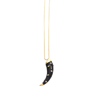 Vintage golden necklace with black horn pendant and gold dot details on white background