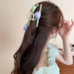 Detail of tulip-shaped acrylic hair claw clip used in a side hairstyle for women