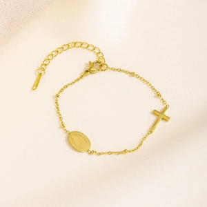 Minimalist gold chain bracelet featuring a cross charm and oval religious coin medal pendant
