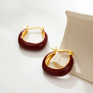 Dettaglio macro dello smalto rosso vino su orecchini a cerchio a U placcati oro 18K