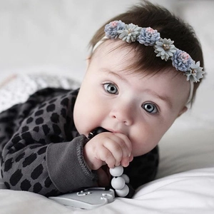 Detail of floral baby headband featuring artificial 3D flowers and small beads on infant