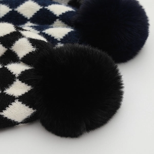 Close-up of knit texture on baby plaid beanie with soft faux fur pom pom detail