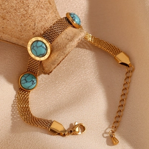 Detail of gold mesh chain bracelet with turquoise stone inlays on textured pottery