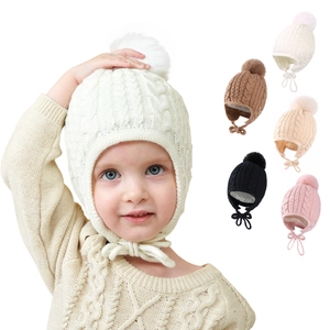 Detail of cable knit texture and faux fur pompom on infant earflap winter hats