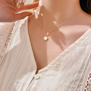 Détail d'un collier en nacre plaqué or avec pendentif papillon porté par un mannequin