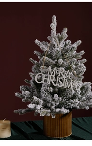 Close-up of a snow-flocked Christmas tree with a silver Merry Christmas glitter sign