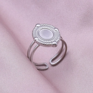 Detail of oval stainless steel ring with radial grooves and adjustable open band on pink silk