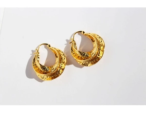 Close-up of golden earrings with hammered texture and double-layered twisted design