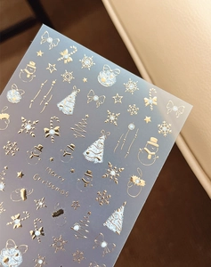 Close-up of gold and silver Christmas nail stickers with snowflakes and reindeer designs