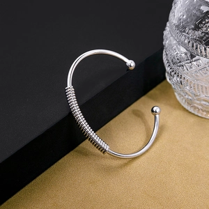 Detail of silver C-shaped cuff bracelet with polished finish and twisted wire knot design