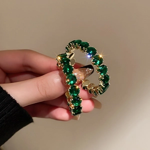 Detail of a vintage emerald green crystal ring hair tie with golden metal base