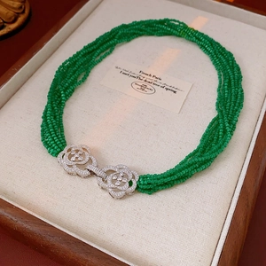 Macro detail of multi-strand emerald green bead necklace with crystal camellia clasp