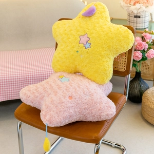 Plush star-shaped pillows in yellow and pink on a brown chair with cute embroidery