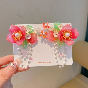 Detailed shot of pink resin flower hair clip with pearl tassels and green leaf accents