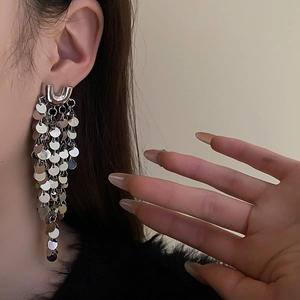 Gros plan détaillé des boucles d'oreilles pompons argentées en forme de U sur le mannequin
