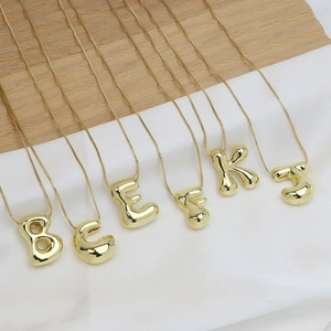 Gold plated brass 18k balloon bubble initial necklaces on white silk and wood