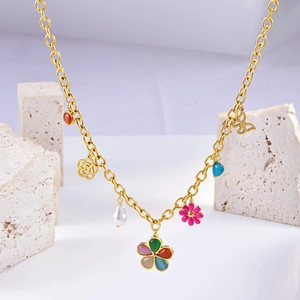 Detail of vintage gold chain necklace with colorful enamel charms and baroque pearl