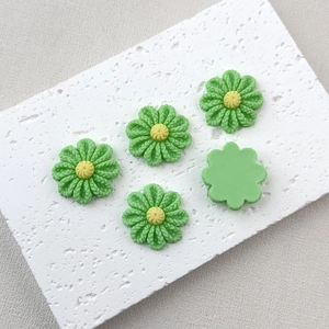 Detail of green resin daisy charms with yellow centers and flat back for DIY crafts