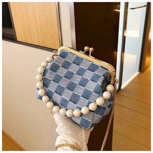 Detail of blue denim checkerboard bag with faux pearl handle and gold clasp closure