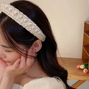 Close-up of elegant cream white fabric headband with polished faux pearls on model