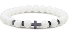 Detail shot of white beaded bracelet featuring a black hematite cross and metal spacers