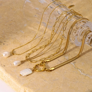 Colliers en acier inoxydable doré avec perles naturelles sur fond de pierre beige