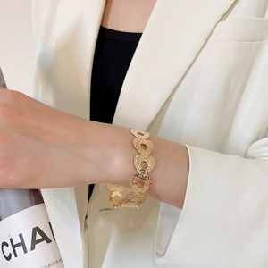 Detailed view of golden heart-shaped bracelet with hammered texture on a female wrist