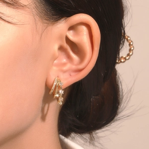Close-up of triple-layered gold earrings with zircon stones and star pendants on a model