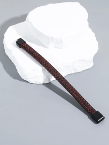 Detail of dark brown braided leather bracelet with black magnetic clasp on white stone