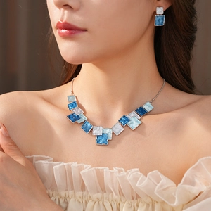 Detail of blue geometric square enamel necklace and earring set on model's neck