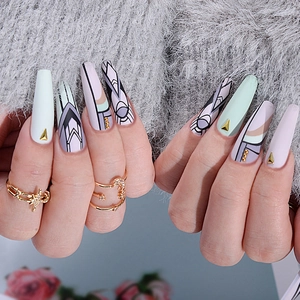 Detailed view of mint green and lavender long coffin nails with gold stud accents