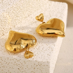 French minimalist 18K gold plated hollow heart earrings on textured stone surface