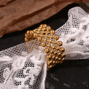 Detail of gold-plated stainless steel mesh cross ring with beaded texture and multi-layer design